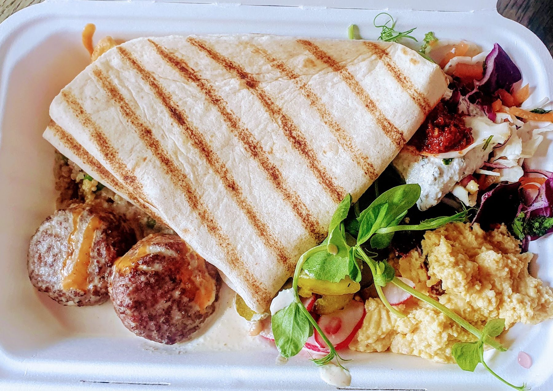 Grilled flatbread with falafel, salad and rice in a takeaway box